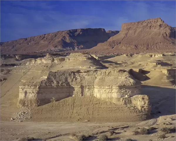 Rock cliffs and sand dunes in front of the fortress of Masada, in the Judean Desert