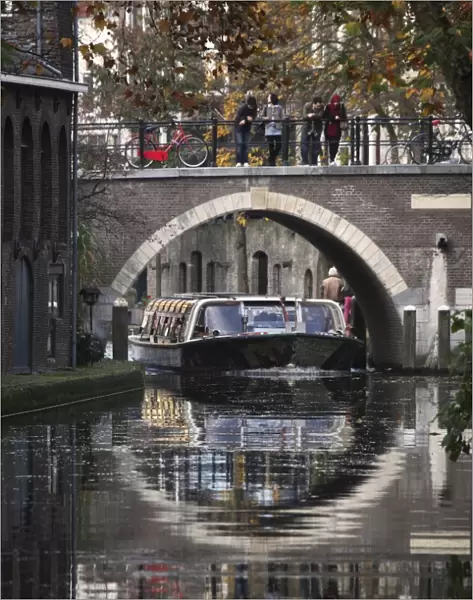 A sightseeing barge under a bridge on the Oudegracht Canal in the Dutch city of Utrecht