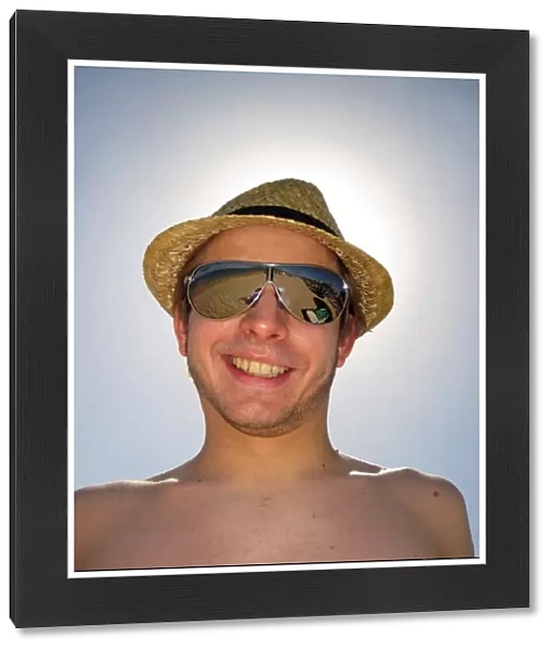 Portrait of a smiling man on summer holiday wearing a straw hat