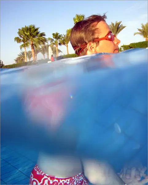 Man swimming underwater in a swimming pool wearing goggles