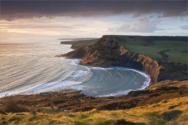 Storm light illuminates Chapmans Pool and Houns Tout cliff, viewed from St Aldhelms Head
