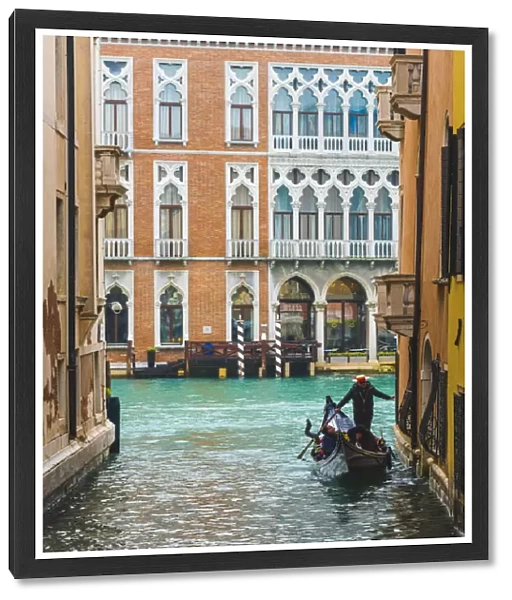 Waterfront palaces and tourists on gondola in a narrow canal tributary of the Grand Canal