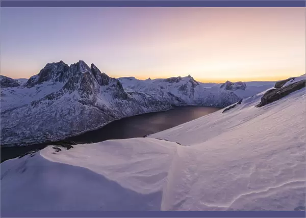 Sunset lights up the snowy peak of Mount Breidtinden and the icy sea along the Mefjorden Berg Senja Tromso Norway Europe