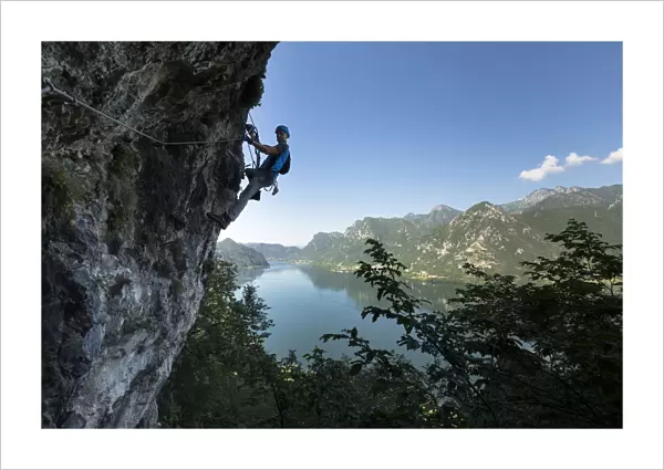 a hiker is climbing along the Ginestre klettersteig with the lake Idro in the background