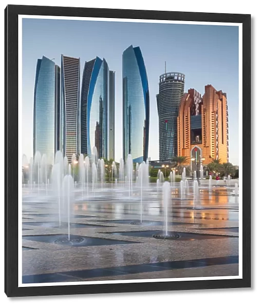 UAE, Abu Dhabi, Etihad Towers and Emirates Palace Hotel fountains, dusk