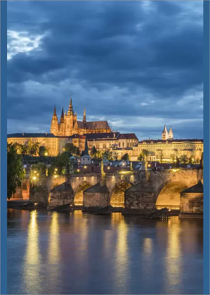 Illuminated Prague Castle and Charles Bridge against cloudy sky at night, Prague, Bohemia