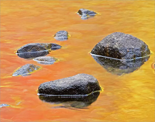 Rocks in Dryberry Creek with autumn colored reflections of trees Sioux Narrows, Ontario, Canada