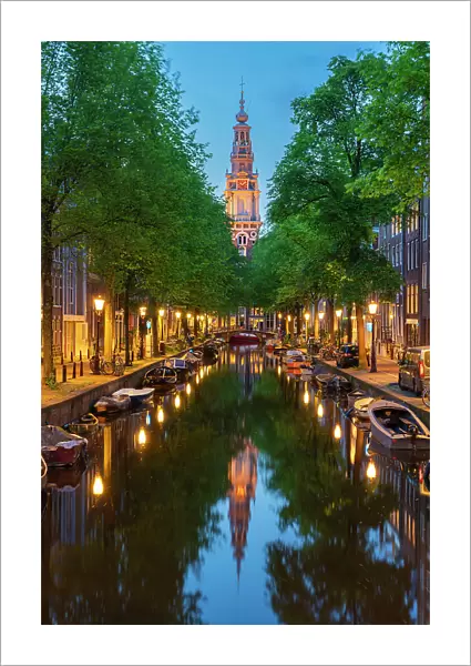 Zuiderkerk Tower near trees and buildings at Groenburgwal canal at twilight, Nieuwmarkt, Amsterdam, Netherlands