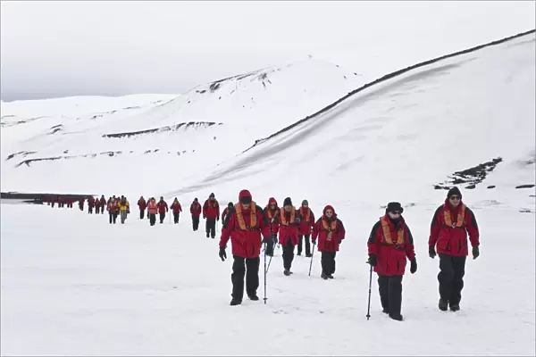 Lindblad Expeditions guests hiking on shorefast ice inside the caldera on Deception Island in Antarctica as part of expedition travel. NO MODEL RELEASES FOR THIS IMAGE