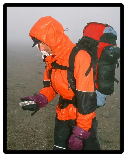 A mountaineer navigating in the Cairngorm mountains in the mist and rain in Scotland