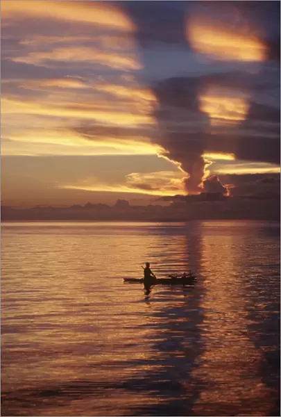Person in canoe on sunset-orange lagoon. Papua New Guinea