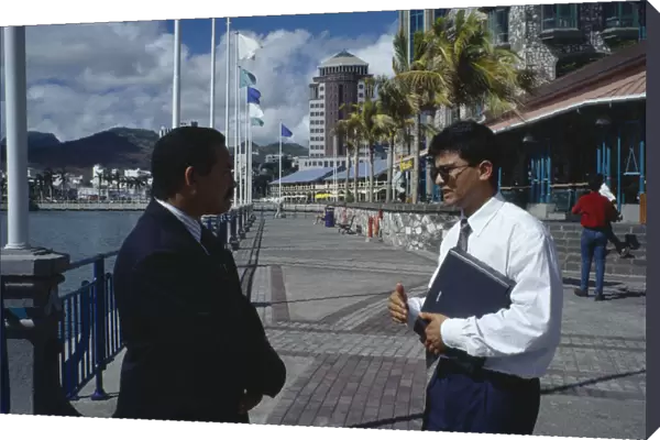 20076232. MAURITIUS Port Louis Two businessmen in conversation on the town waterfront