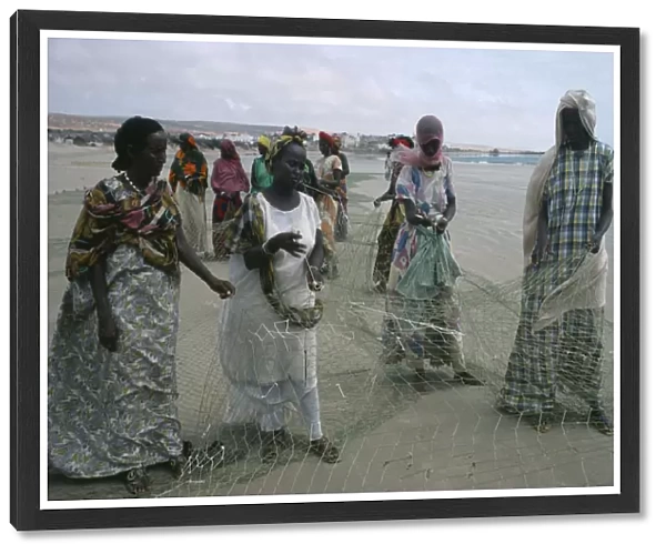 20053340. SOMALIA Industry Settled nomad women mending fishing net on shore of beach