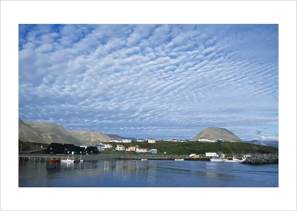 Iceland, Skagafjorour, Hofsos Island, Seaside village with boats on water and houses built along shoreline