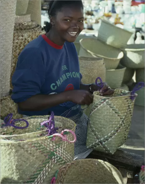 20076092. MADAGASCAR Antananarivo Girl making rafia baskets on market stall. Tana craft