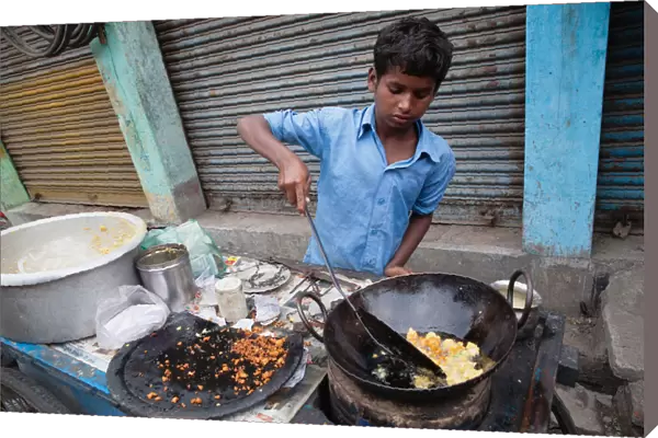 India, West Bengal, Asansol, A boy fries chilli pakora on a street food cart