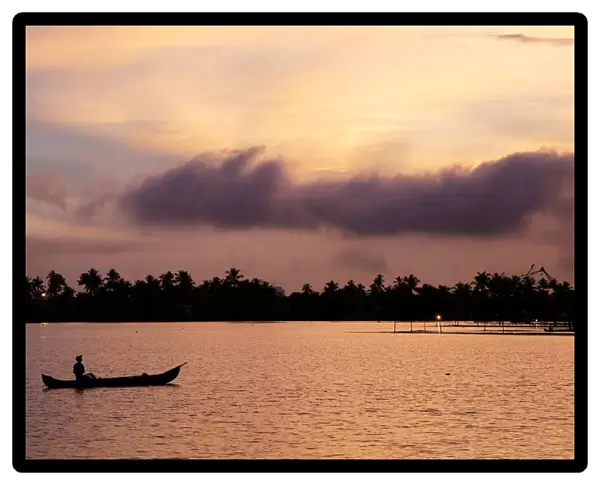 A man rows his boat in the tributary waters of Vembanad Lake against the backdrop