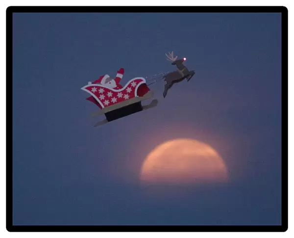 A 10-foot long remote controlled flying Santa makes a test flight past a setting moon