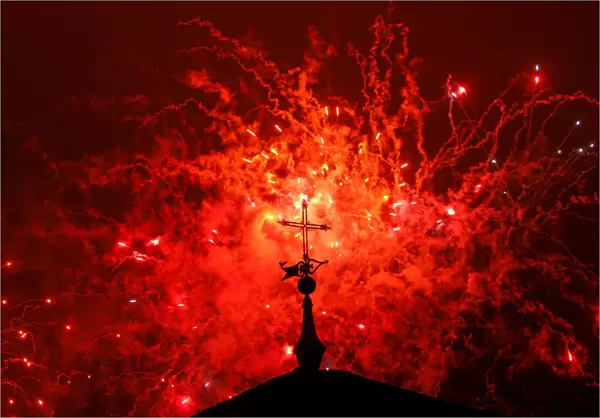 A cross of the Basilica of the Agustinas Recoletas is seen as fireworks explode over