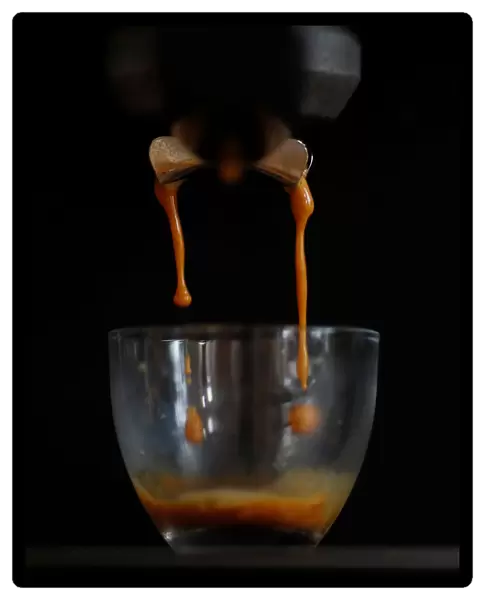 Freshly ground Arabica coffee drips from a domestic coffee machine to make an espresso