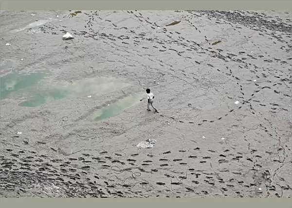A boy walks along the banks of the river Ganga, in Allahabad