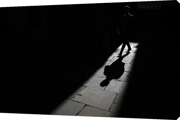A man casts a shadow as he walks along an alleyway in central London
