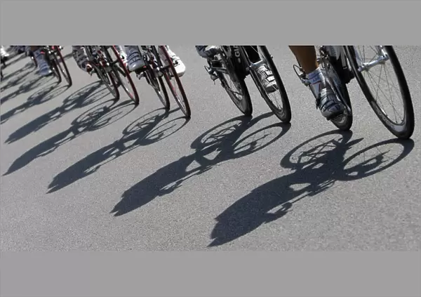Shadows are cast on the road as the pack of riders cycles during the twelfth stage
