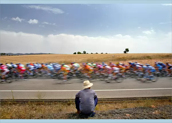 A man looks at a pack of riders cycle during the fifth stage of the Tour of Spain