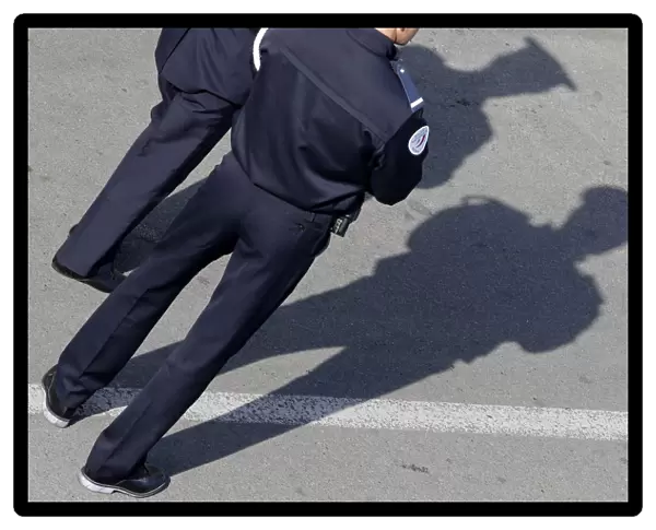 French policemen cast their shadows on the pavement as they stand guard near the Festival
