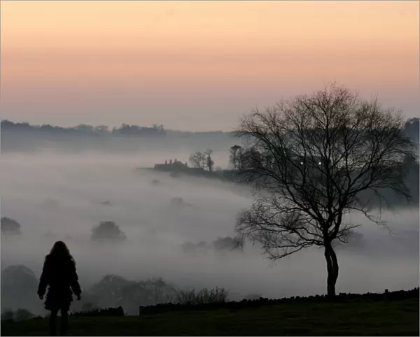 A girl looks out over fog covered Leicestershire countryside