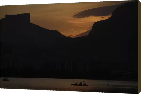 People paddle their canoe at Rodrigo de Freitas Lagoon as the sun sets in Rio de Janeiro