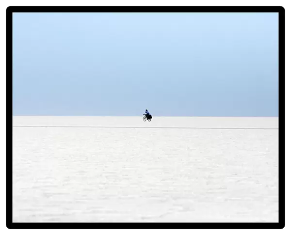 A man rides a bicycle on the surface of the worlds largest salt flat, the Salar de Uyuni