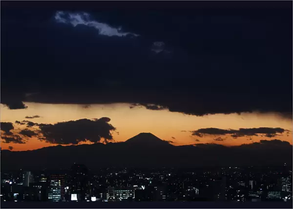 The silhouette of Japans highest mountain Mount Fuji is seen beyond buildings in Tokyo