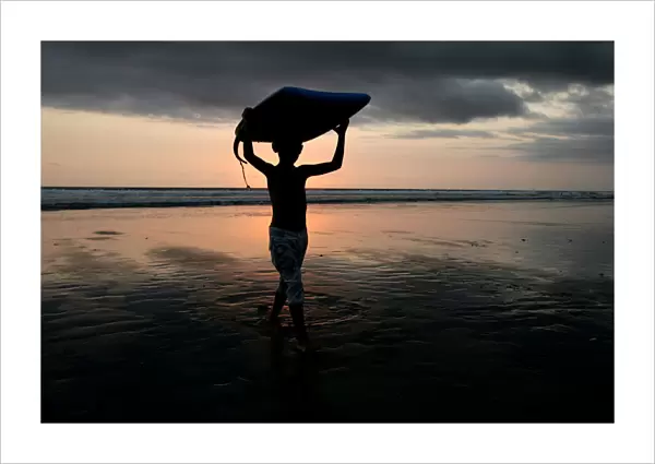 A boy carries his boogie board near Kuta beach on the Indonesian resort island of Bali