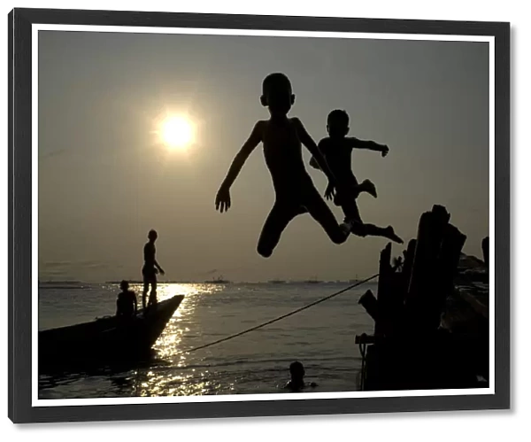 Children jump into the sea at Marunda beach in Jakarta