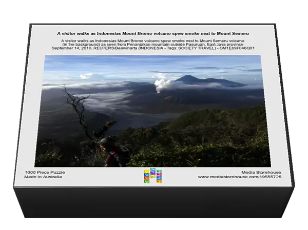 A visitor walks as Indonesias Mount Bromo volcano spew smoke next to Mount Semeru