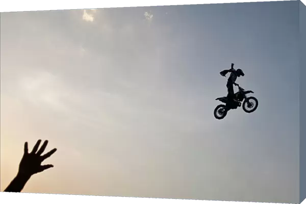 A member of audience waves at a rider performing a stunt during the Red Bull X-Fighters