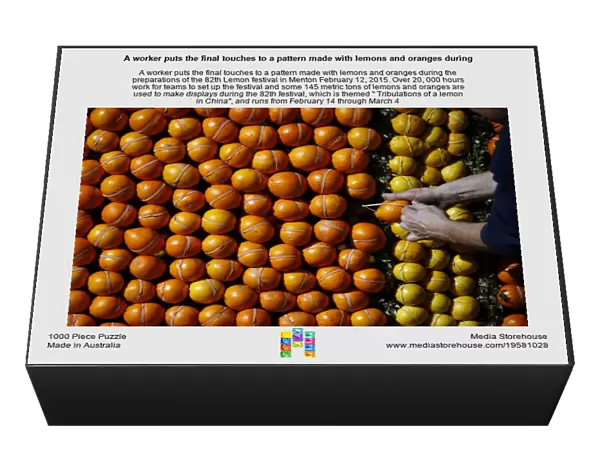 A worker puts the final touches to a pattern made with lemons and oranges during the