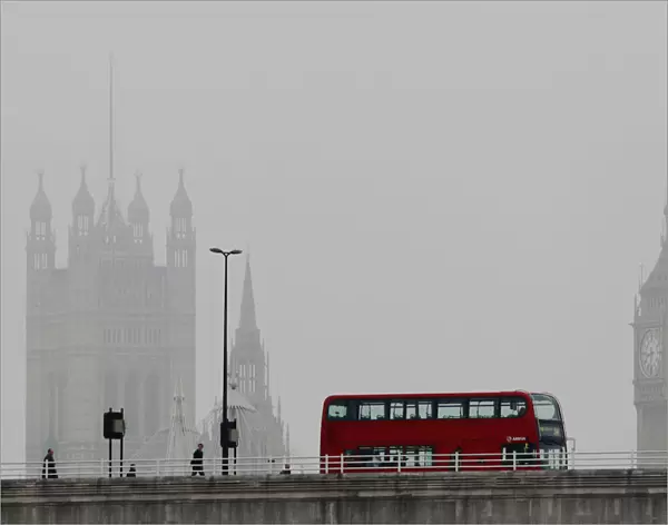 A bus crosses Waterloo bridge in front of the Houses of Parliament during a misty