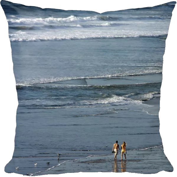 A couple walk along the beach during relatively warm weather in Encinitas