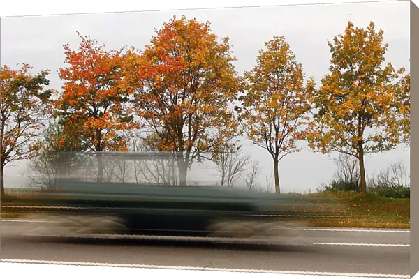 Car speeds alongside autumn trees near village of Zaslavl