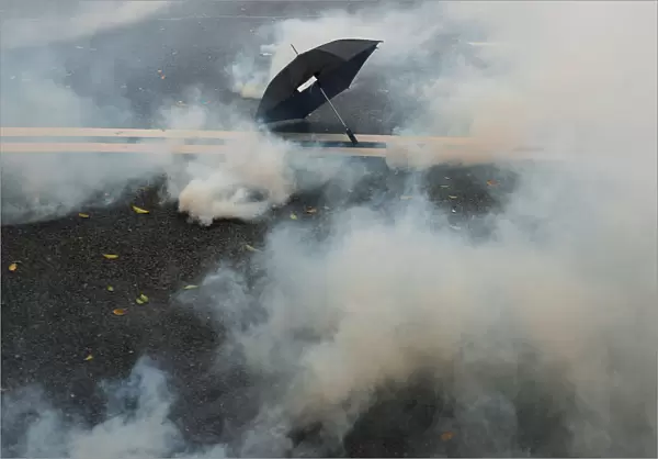 An umbrella lies on the ground surrounded by the mist of tear gas during a demonstration