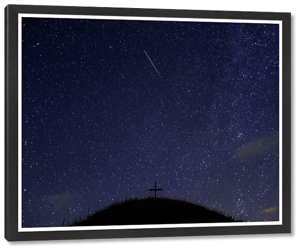 A meteor streaks past stars in the night sky above Leeberg hill during the Perseid meteor