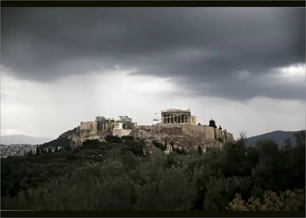 The ancient Parthenon temple is seen atop the Acropolis hill under storm clouds in Athens