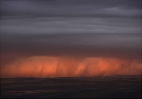 Rain clouds are lit by the setting sun, looking south from Hadrians Wall near Hexham in