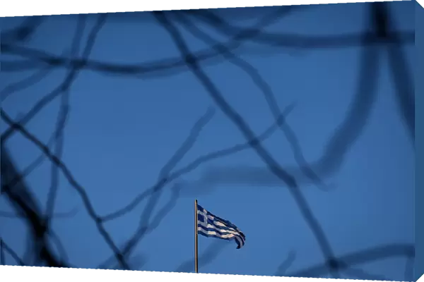 A Greek national flag flutters on the roof of a building in Athens