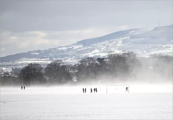 People run on a football field in the snow at the Phoenix Park in Dublin