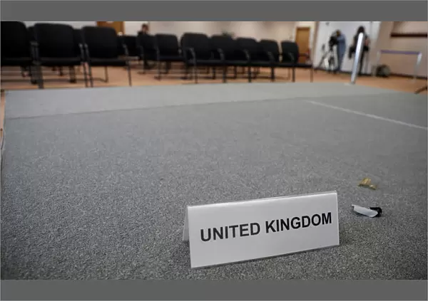 A United Kingdom name card lies on a stage inside the empty British press conference room