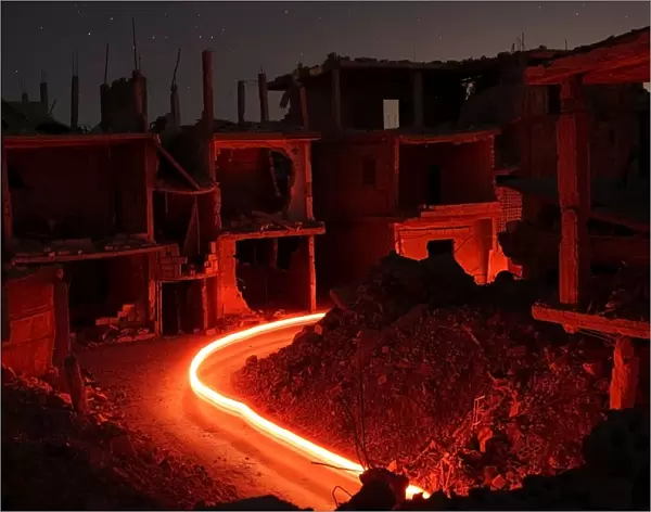 Damaged buildings are pictured at night in the rebel-held area, in the city of Deraa