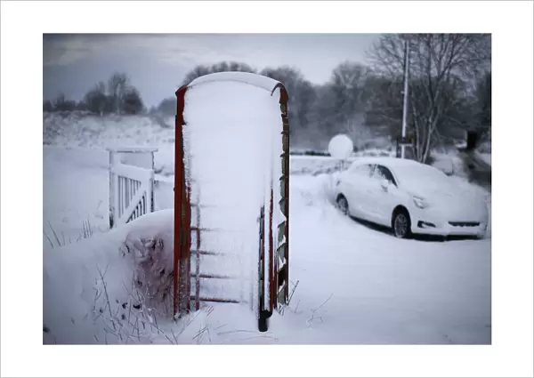 An abandoned car and a telephone box stand in snow near Ashbourne